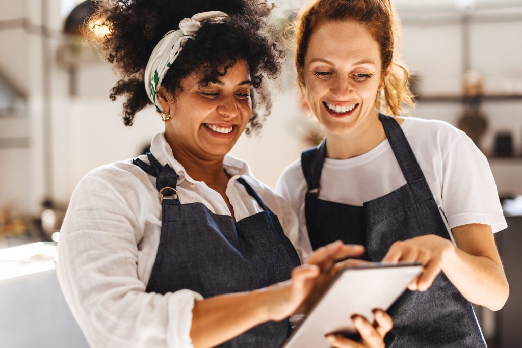 2 female hospitality workers looking at an iPad